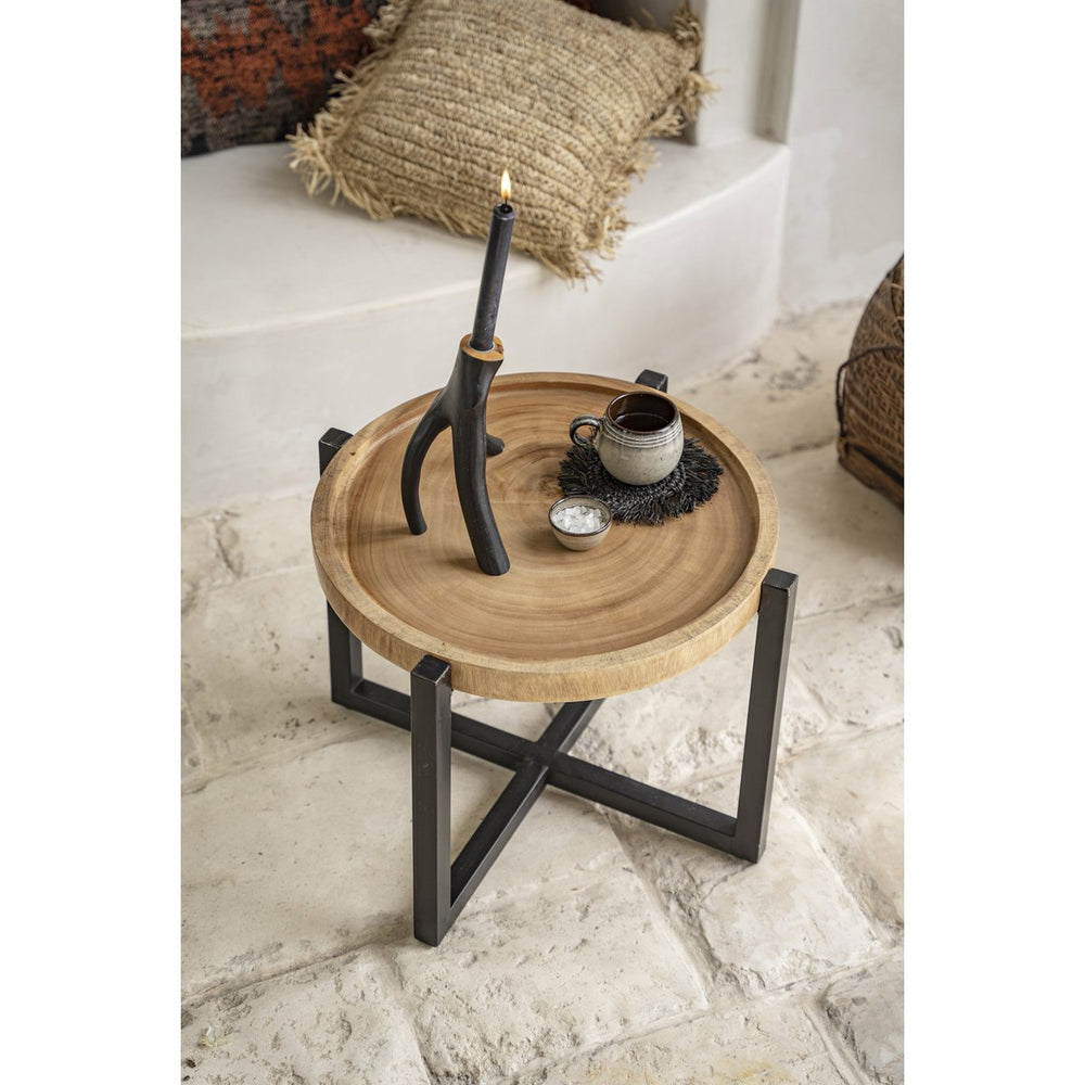 Small round wooden table with metal legs on a marble floor, featuring a candle and decorative items.