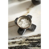 Decorative stone with a small container of crystals on a marble surface